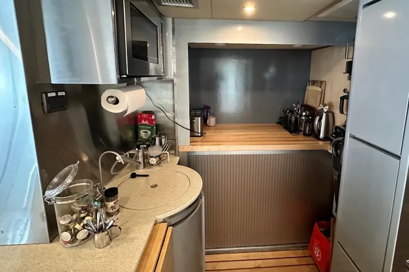 First Home Yacht Photos Pics Compact kitchen in a 1988 Cheoy Lee 92 yacht with modern appliances and wooden countertops.