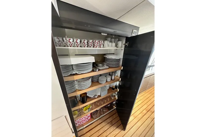 First Home Yacht Photos Pics Open cabinet with neatly arranged dishes and cups on a Cheoy Lee 92 yacht, 1988 model.