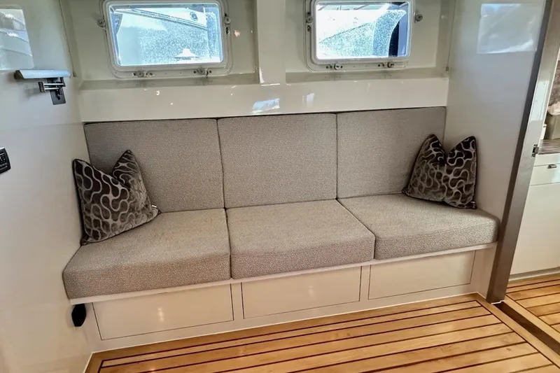 First Home Yacht Photos Pics Elegant interior of 1988 Cheoy Lee 92 yacht with cushioned seating and decorative pillows.