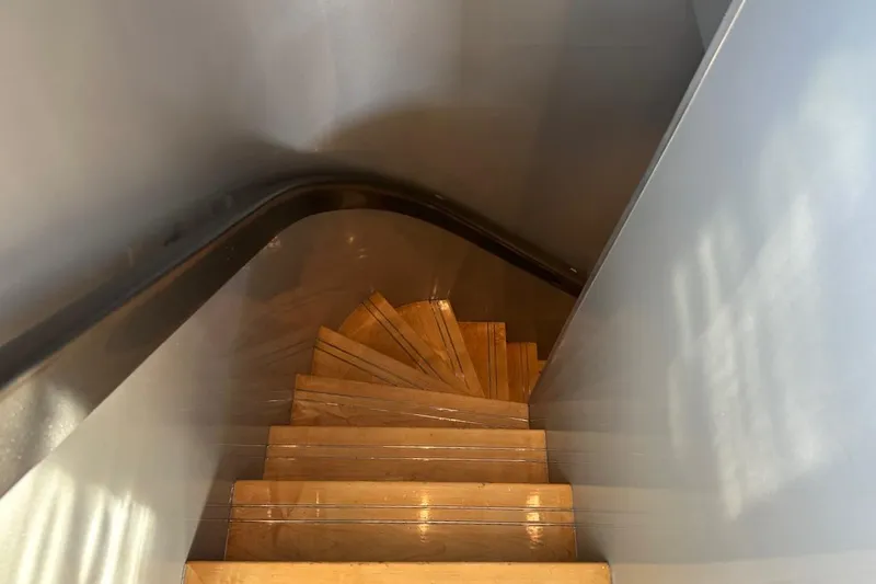 First Home Yacht Photos Pics Wooden spiral staircase inside 1988 Cheoy Lee 92 yacht, featuring sleek modern design.