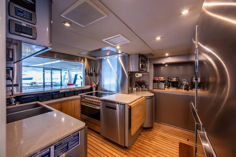 First Home Yacht Photos Pics Luxurious kitchen interior on 1988 Cheoy Lee 92 yacht with modern appliances and wood flooring.