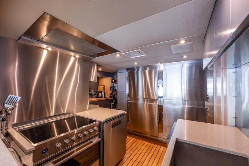 First Home Yacht Photos Pics Luxurious stainless steel kitchen in 1988 Cheoy Lee 92 yacht, featuring modern appliances and wood flooring.