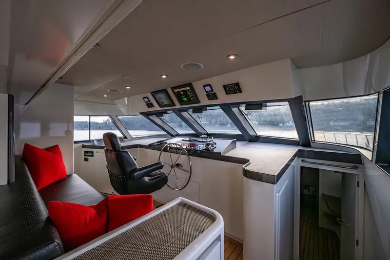 First Home Yacht Photos Pics Interior of 1988 Cheoy Lee 92 yacht helm with modern controls and red cushions.