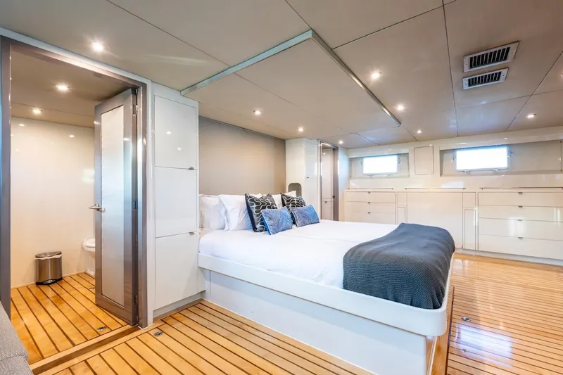 First Home Yacht Photos Pics Luxurious 1988 Cheoy Lee 92 yacht bedroom with modern decor and wooden flooring.