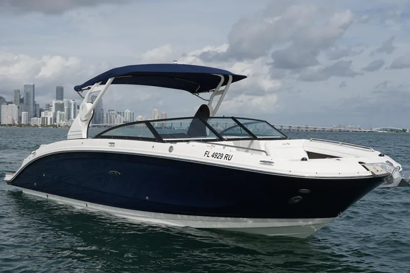  Yacht Photos Pics 2018 Sea Ray SDX 290 boat cruising near city skyline under cloudy sky.