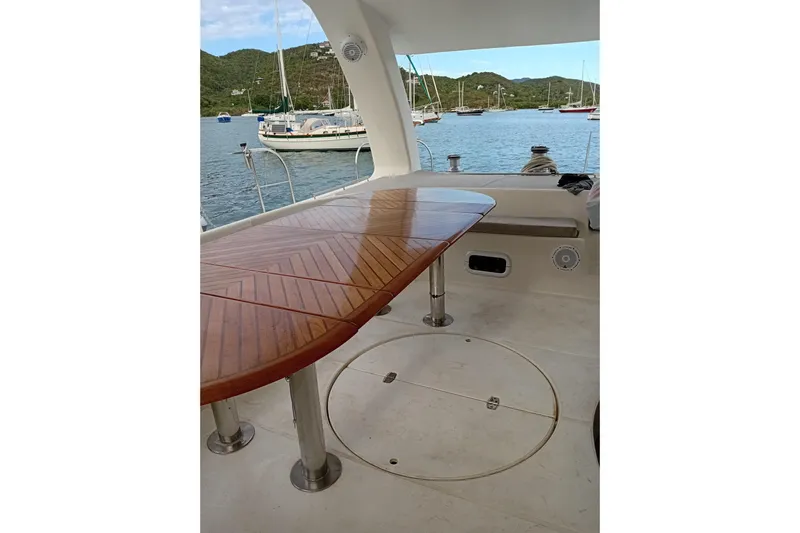  Yacht Photos Pics 1995 Fountaine Pajot Marquises 56 yacht deck with wooden table, overlooking serene waters.