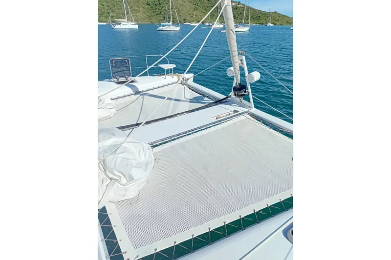  Yacht Photos Pics 1995 Fountaine Pajot Marquises 56 catamaran deck with netting, anchored in serene waters.