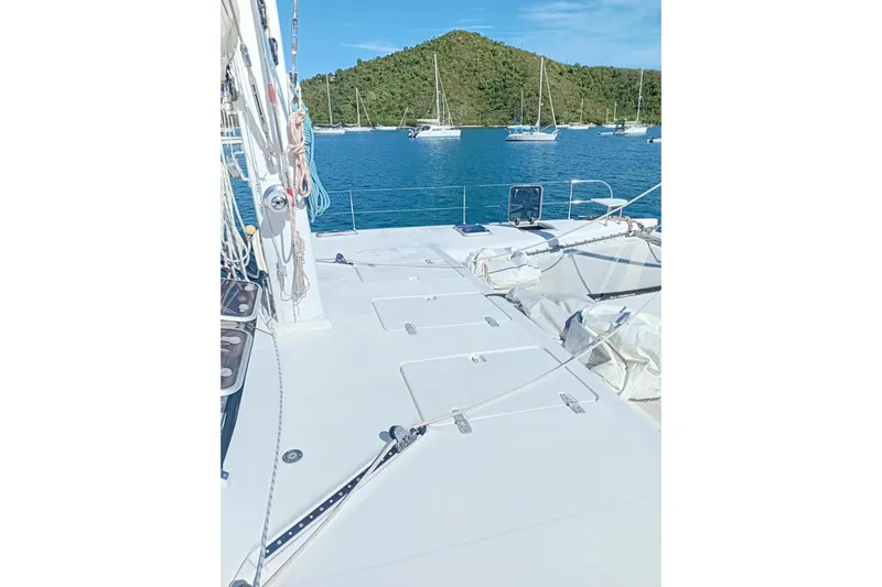  Yacht Photos Pics Deck view of 1995 Fountaine Pajot Marquises 56 catamaran, anchored near lush island.
