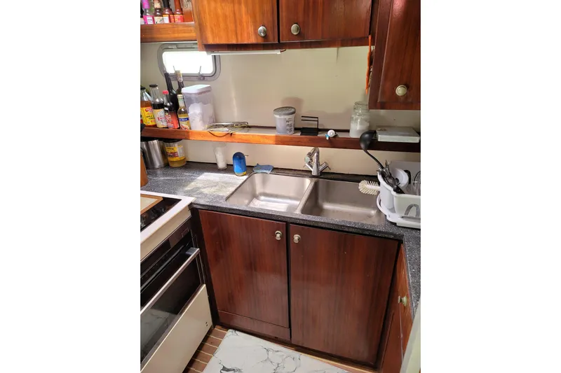  Yacht Photos Pics Galley kitchen in 1995 Fountaine Pajot Marquises 56 catamaran with wooden cabinets and double sink.