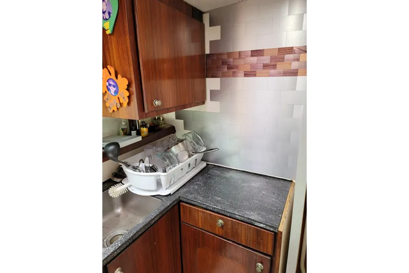  Yacht Photos Pics Galley kitchen in 1995 Fountaine Pajot Marquises 56 catamaran with wooden cabinets and dish rack.