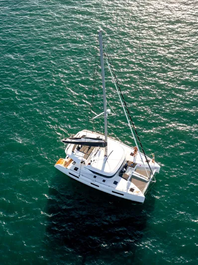 Martina Yacht Photos Pics Aerial view of 2021 Lagoon 46 catamaran sailing on clear blue water.