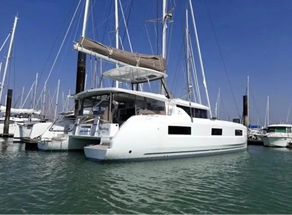 Martina Yacht Photos Pics 2021 Lagoon 46 catamaran docked in a marina under clear blue skies.