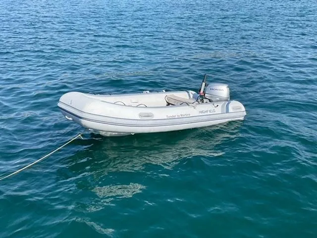 Martina Yacht Photos Pics Inflatable dinghy with Honda motor floating on calm blue water.