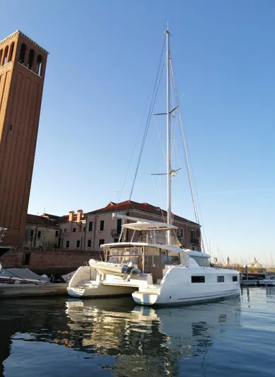 Martina Yacht Photos Pics 2021 Lagoon 46 catamaran docked near historic buildings under clear blue sky.