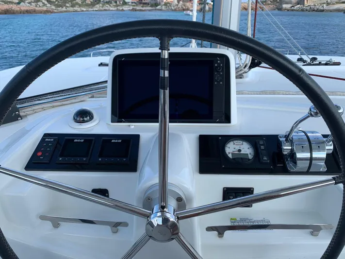 Martina Yacht Photos Pics Steering wheel and controls of a 2021 Lagoon 46 catamaran, overlooking the sea.