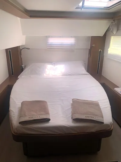 Martina Yacht Photos Pics 2021 Lagoon 46 yacht cabin with double bed, skylight, and neatly arranged towels.