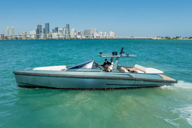 Wally Yacht Photos Pics 2021 Wally 48 Wally Tender yacht cruising in turquoise waters near a city skyline.