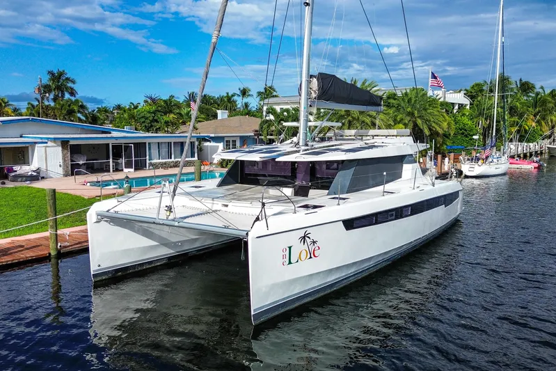 One Love Yacht Photos Pics 2019 Leopard 50 catamaran docked by waterfront homes, under a clear blue sky.