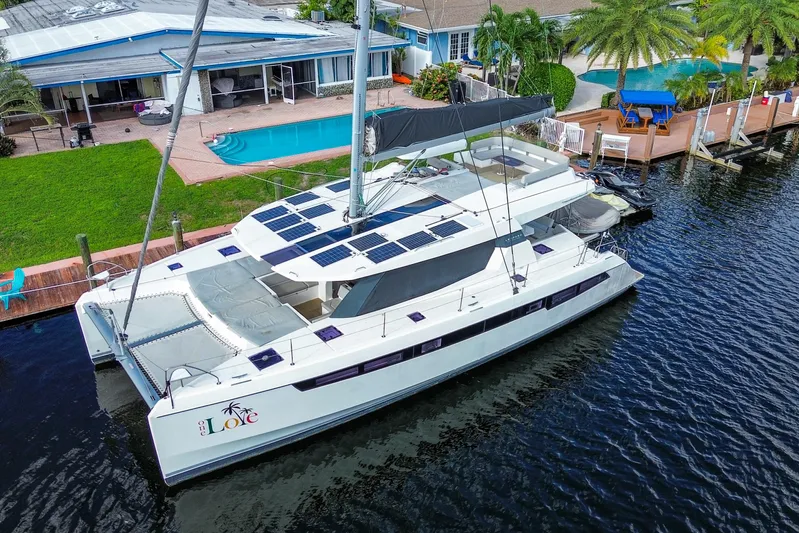One Love Yacht Photos Pics 2019 Leopard 50 catamaran docked by a waterfront home with pool and palm trees.
