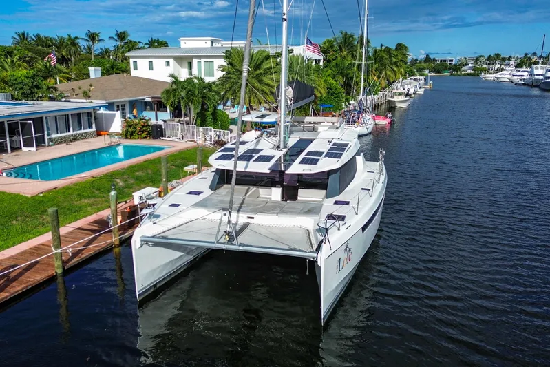 One Love Yacht Photos Pics 2019 Leopard 50 catamaran docked by waterfront homes with pool and palm trees.