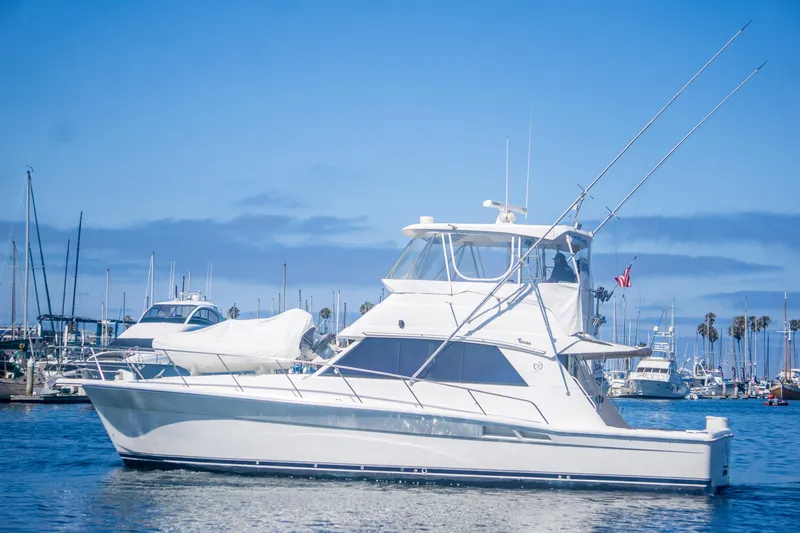 Play’n Hooky Yacht Photos Pics 1999 Riviera 43 Open Flybridge yacht in marina, clear blue sky, calm waters.