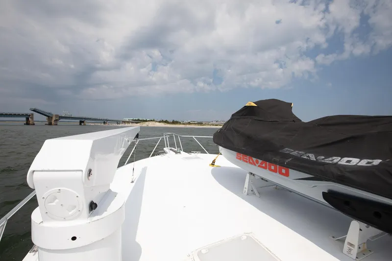 Good To Go Yacht Photos Pics 2002 Viking 61 yacht deck with covered Sea-Doo, bridge in background, cloudy sky.