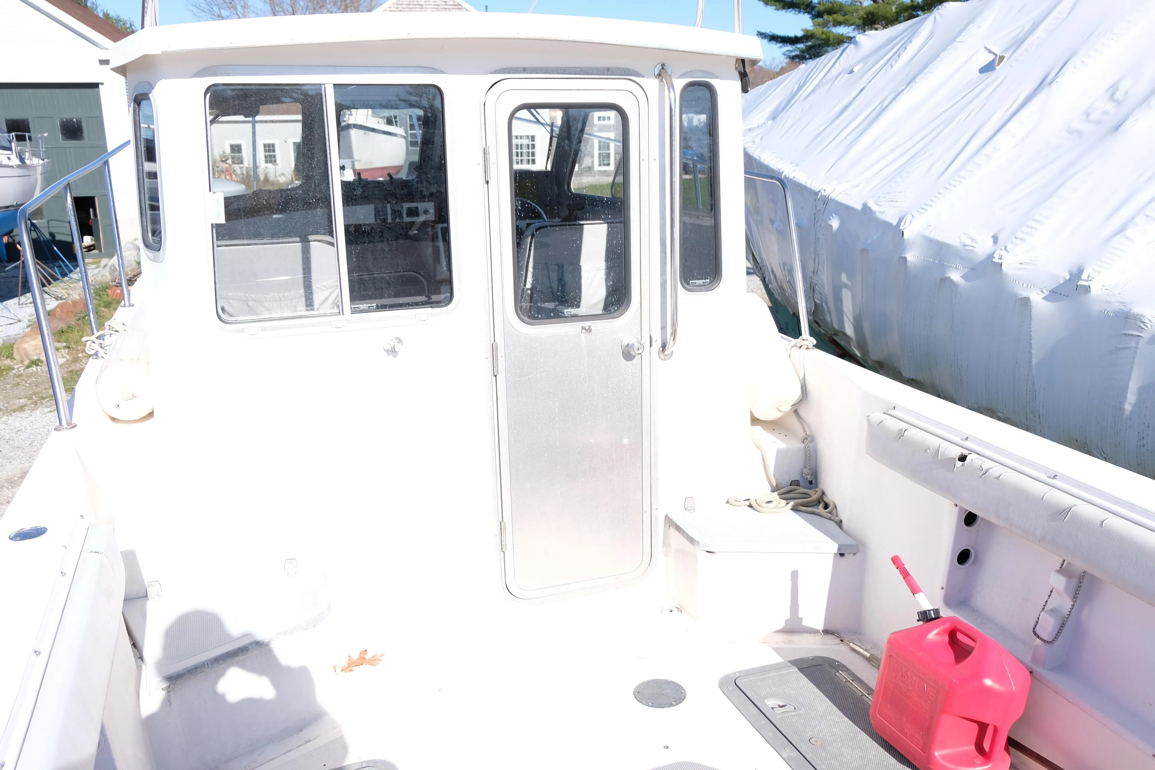 1999 Osprey 24 boat with cabin, docked outdoors, red fuel container on deck.