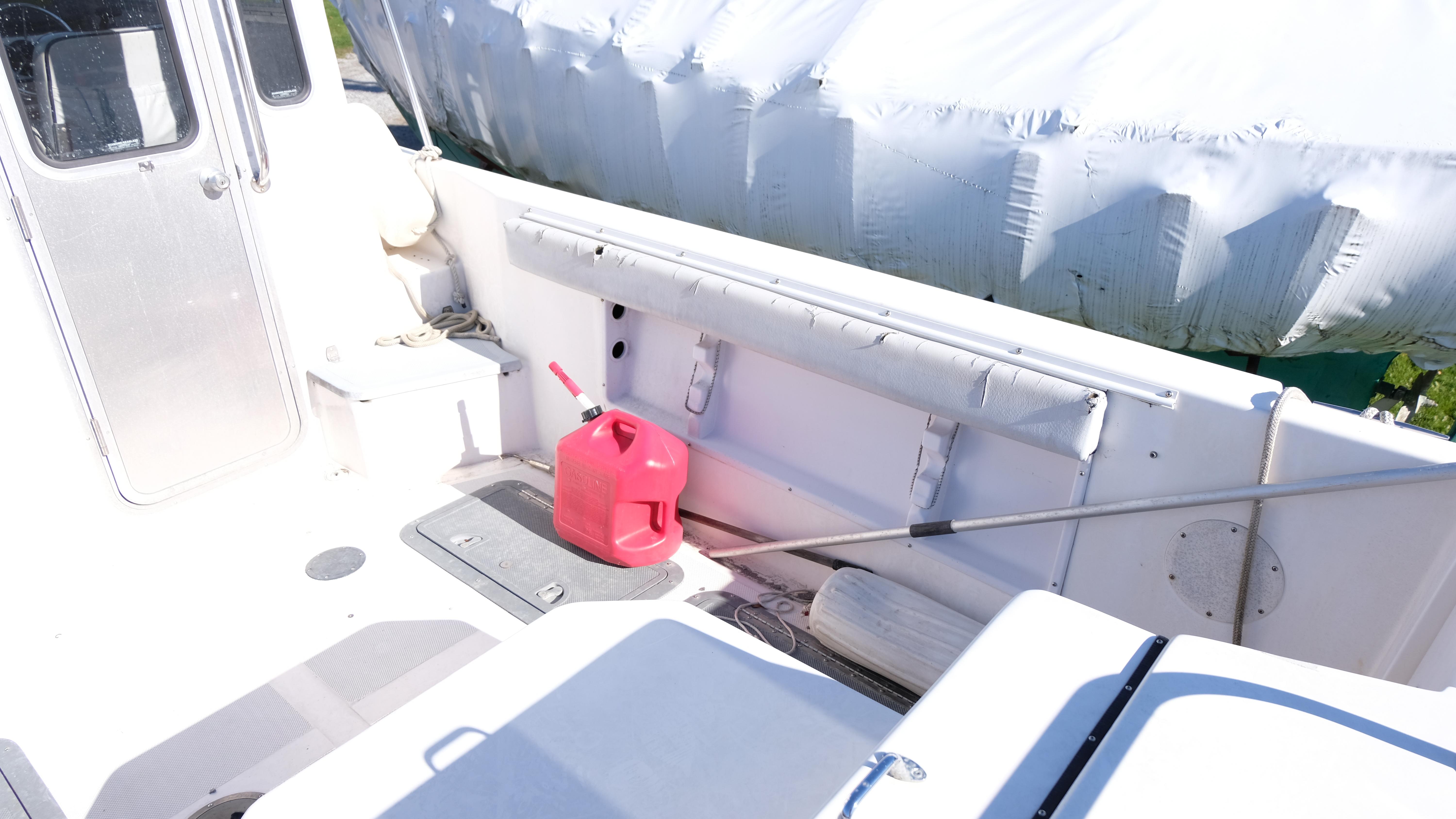 1999 Osprey 24 boat deck with red fuel can and covered equipment.