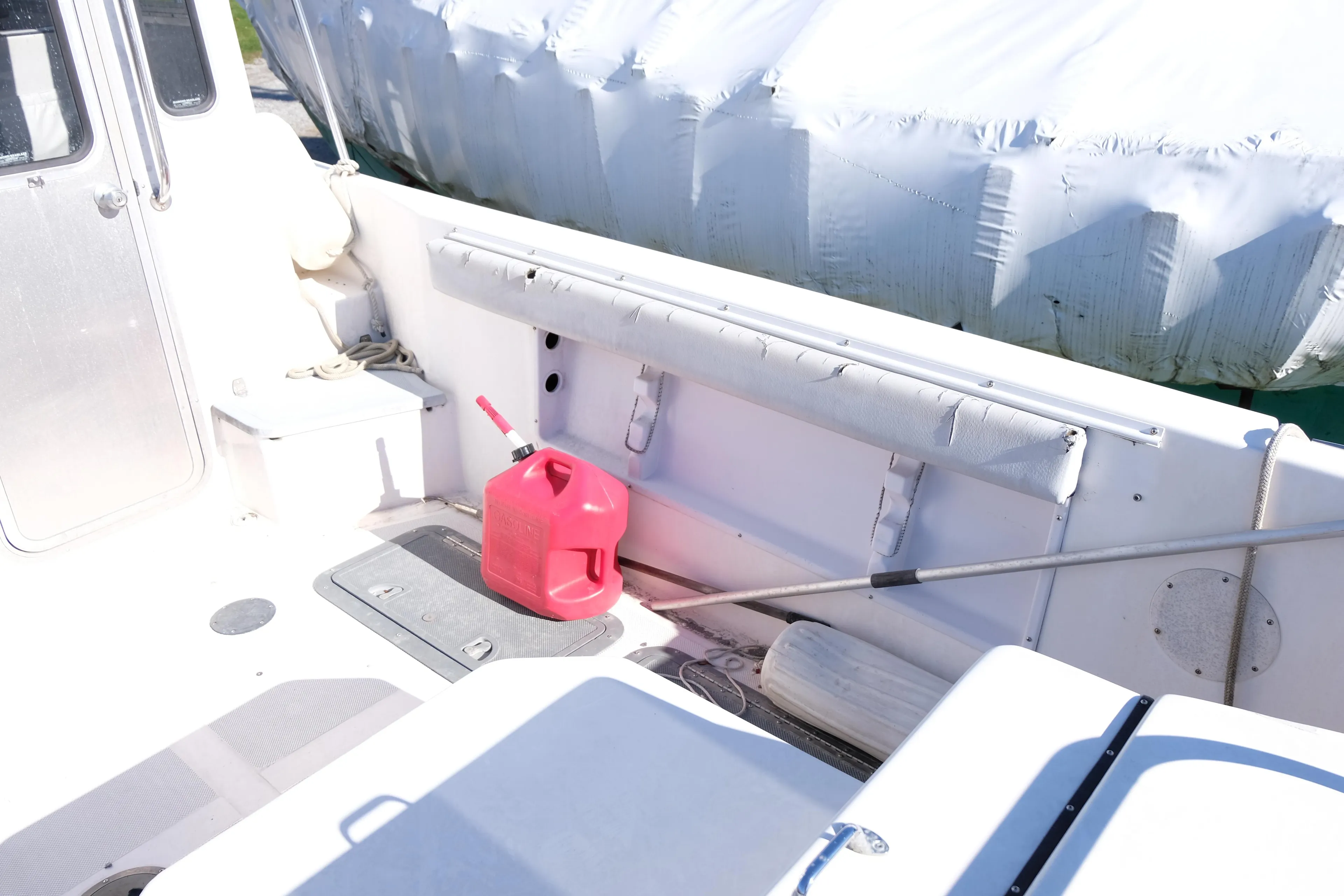 1999 Osprey 24 boat deck with red fuel can and covered equipment.