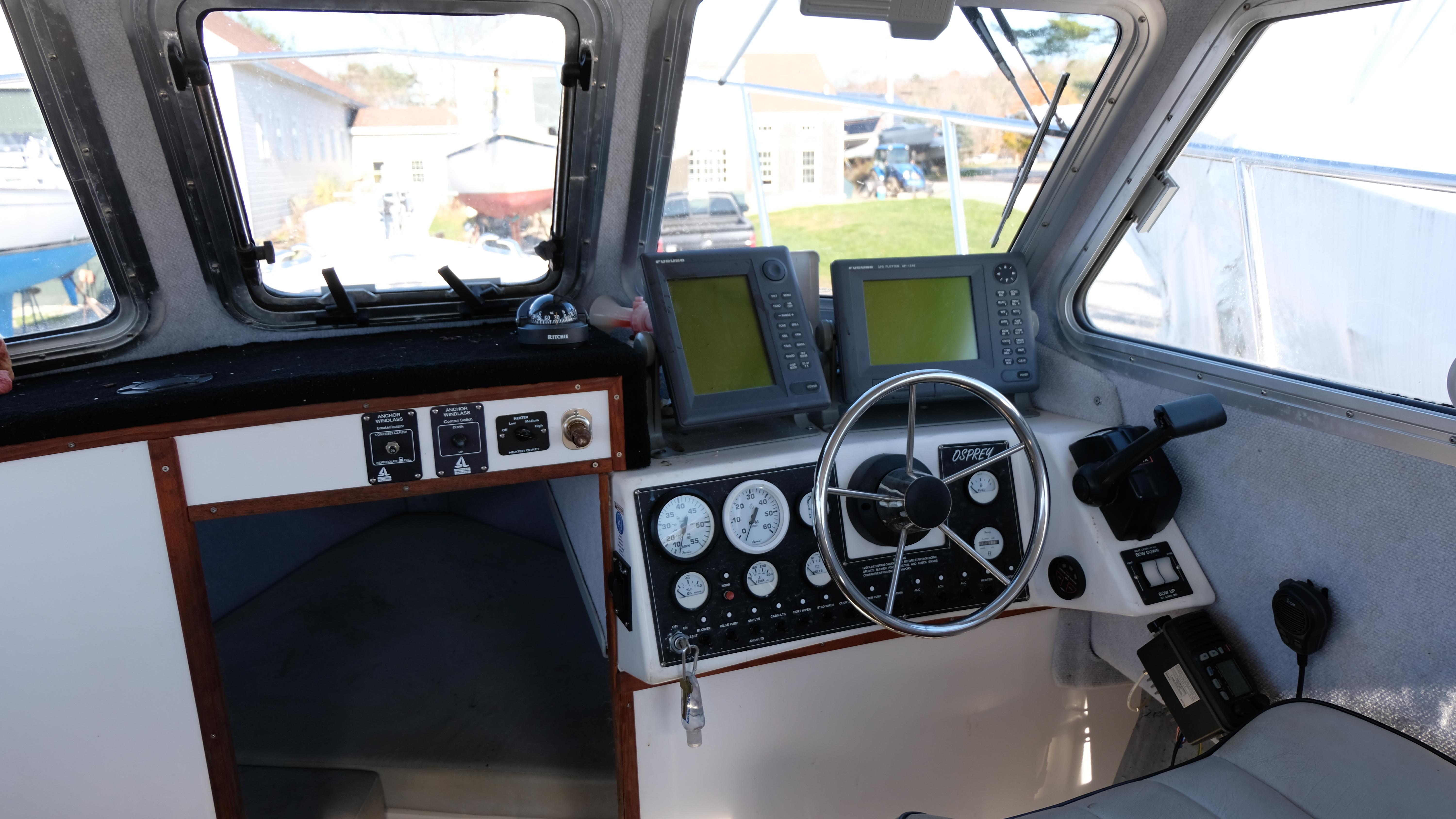 Interior of a 1999 Osprey 24 boat cockpit with navigation instruments and steering wheel.