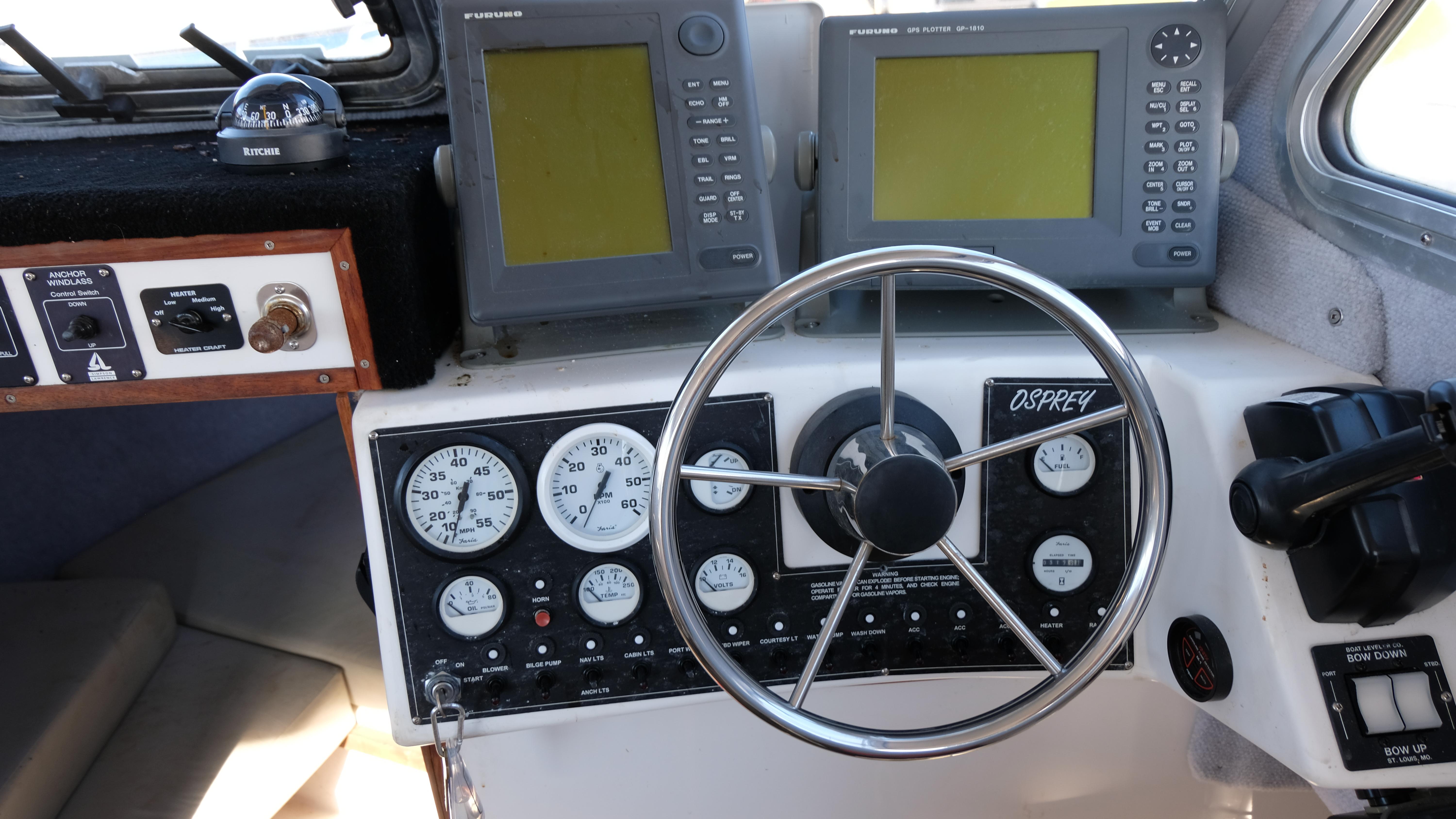 1999 Osprey 24 boat dashboard with steering wheel, gauges, and navigation screens.