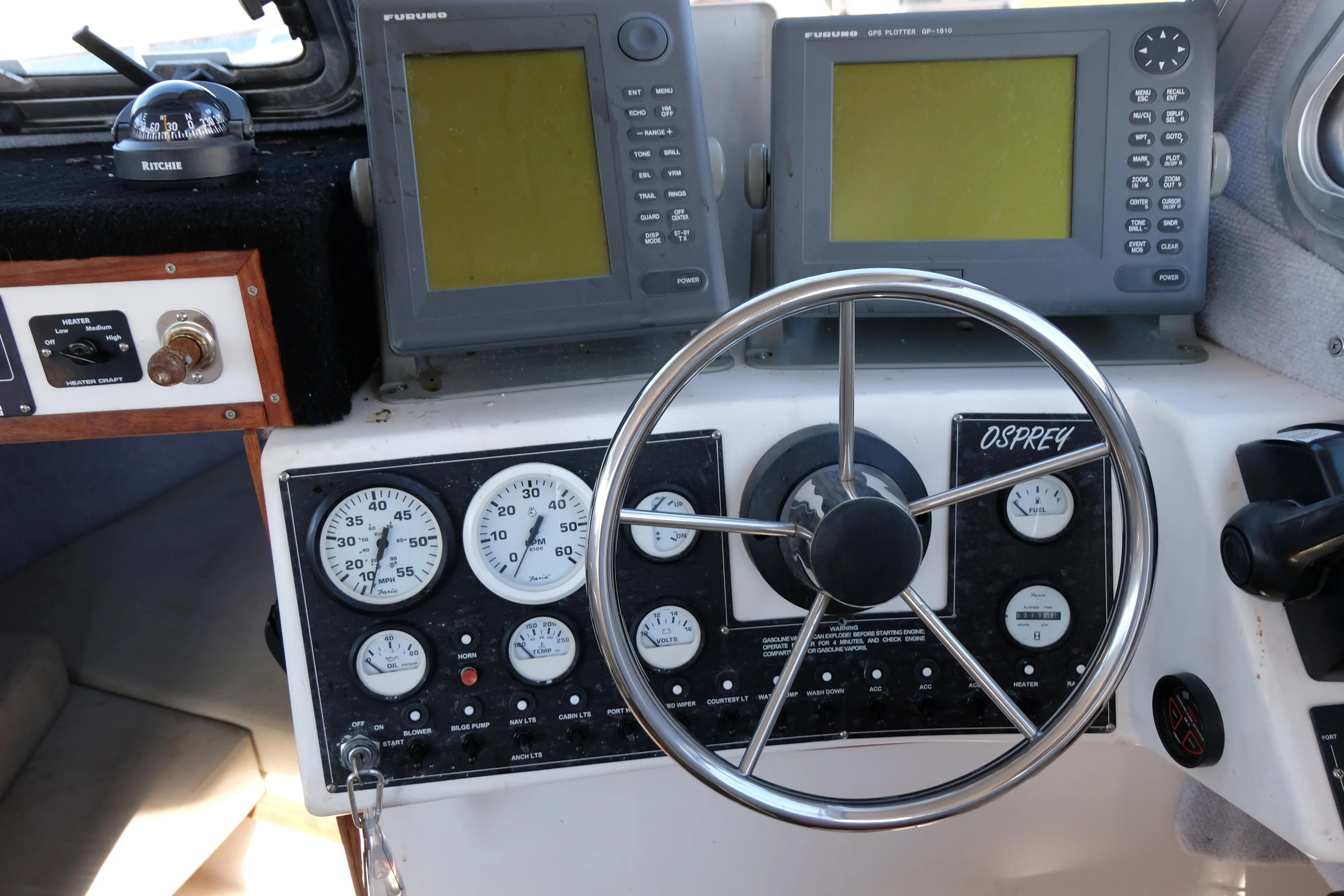 1999 Osprey 24 boat dashboard with steering wheel, gauges, and navigation screens.