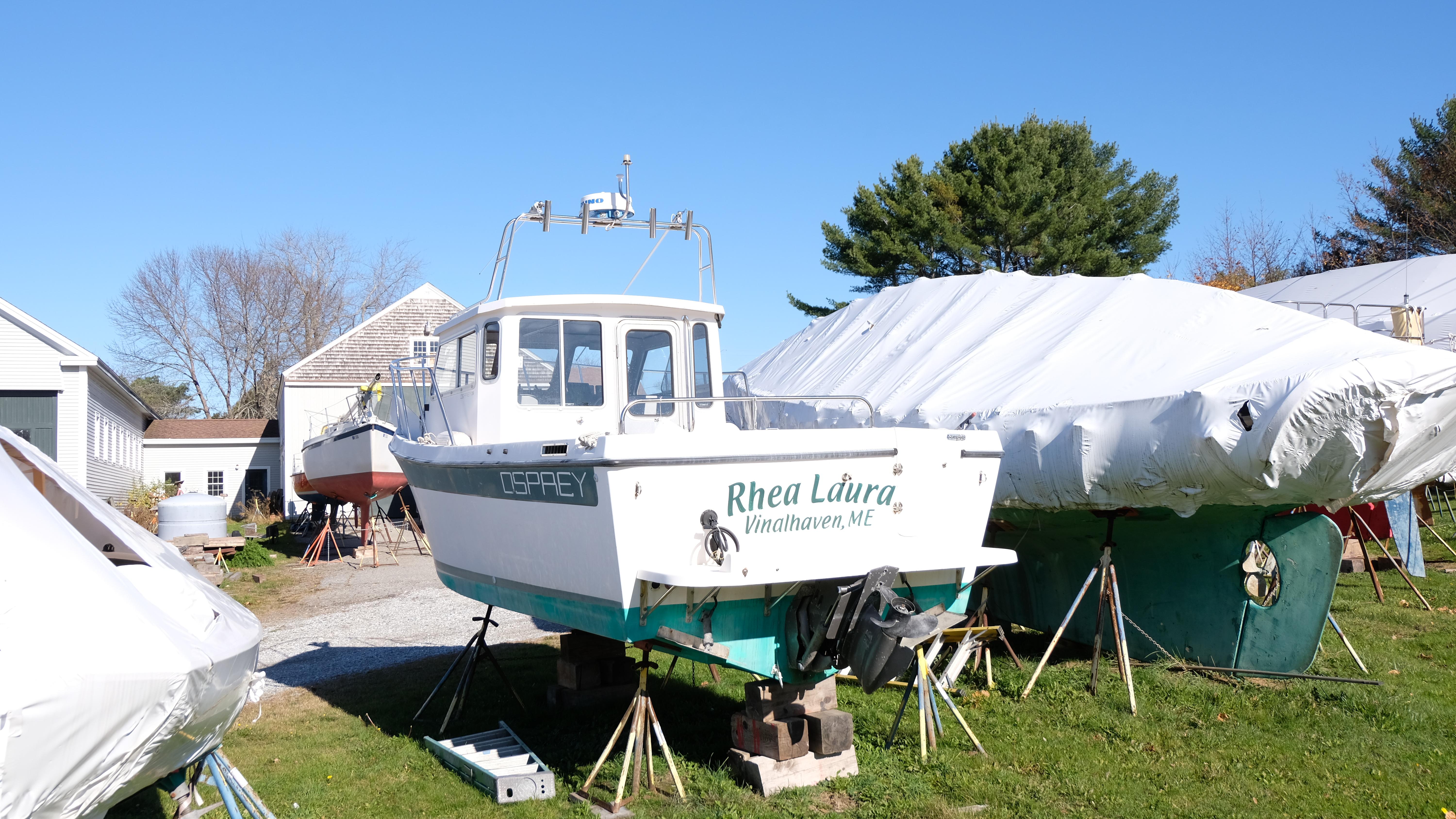1999 Osprey 24 boat "Rhea Laura" on land, surrounded by covered boats.
