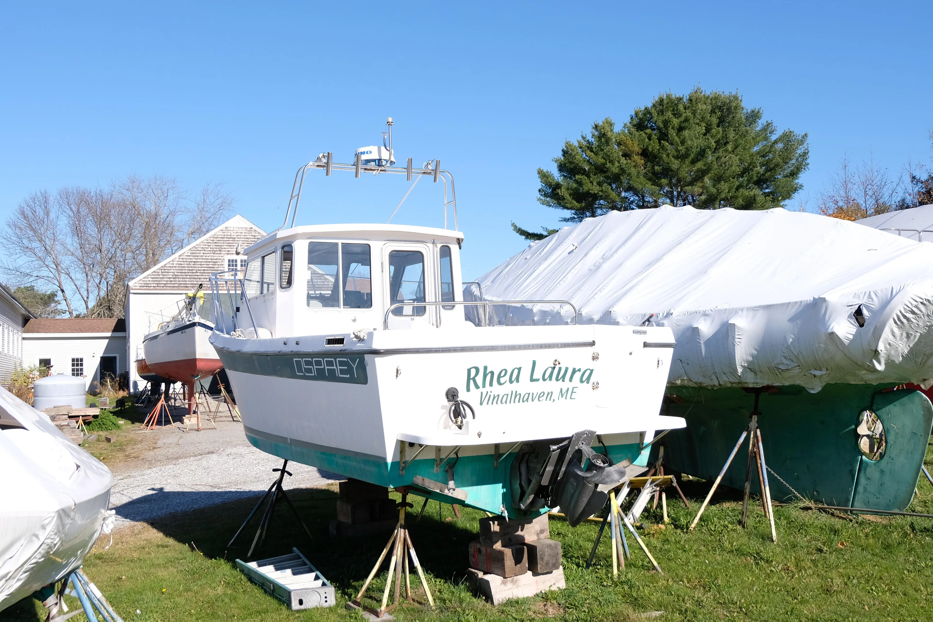 1999 Osprey 24 boat "Rhea Laura" on land, surrounded by covered boats.