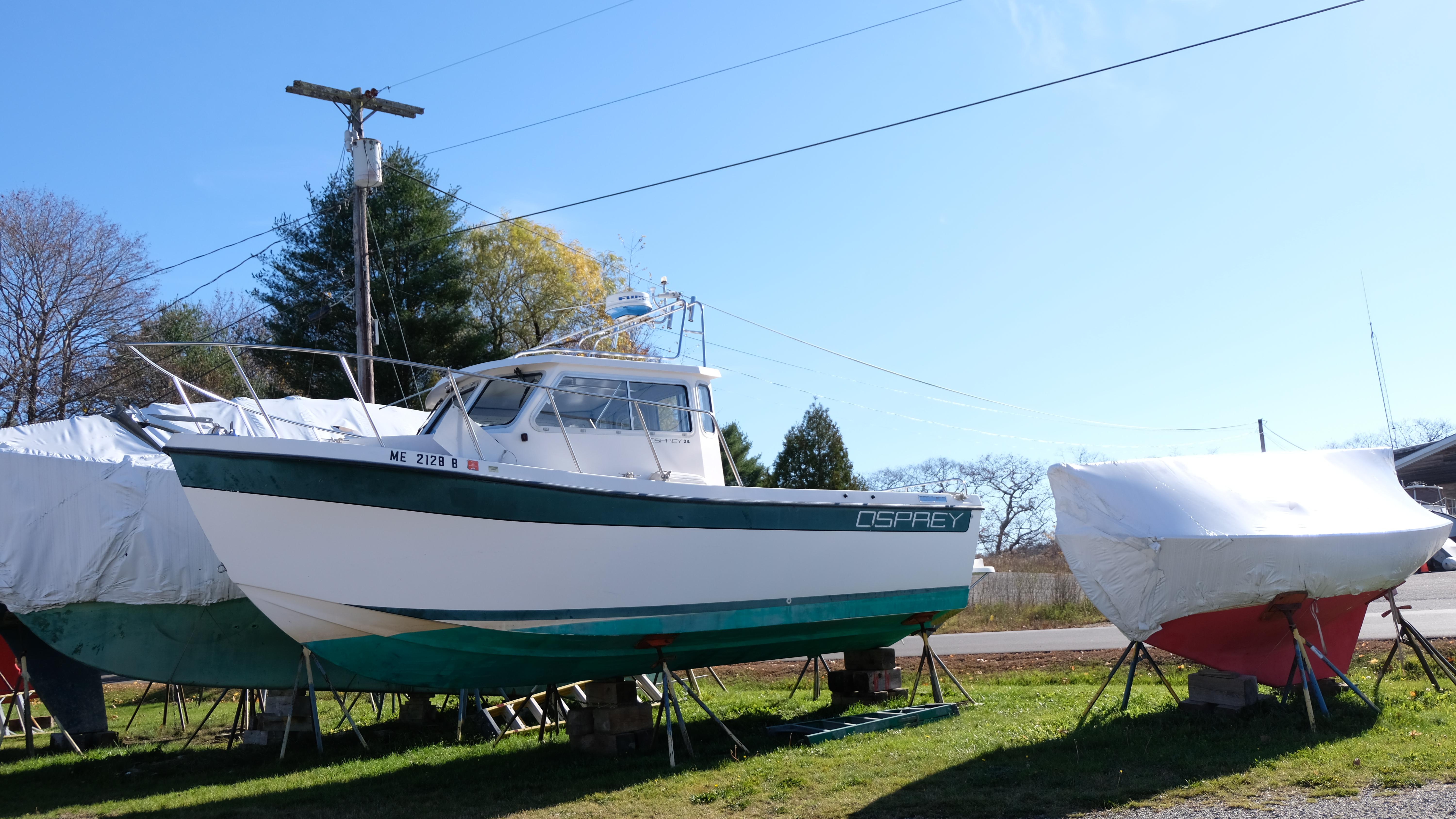 1999 Osprey 24 boat on stands, surrounded by covered boats, in a sunny outdoor setting.