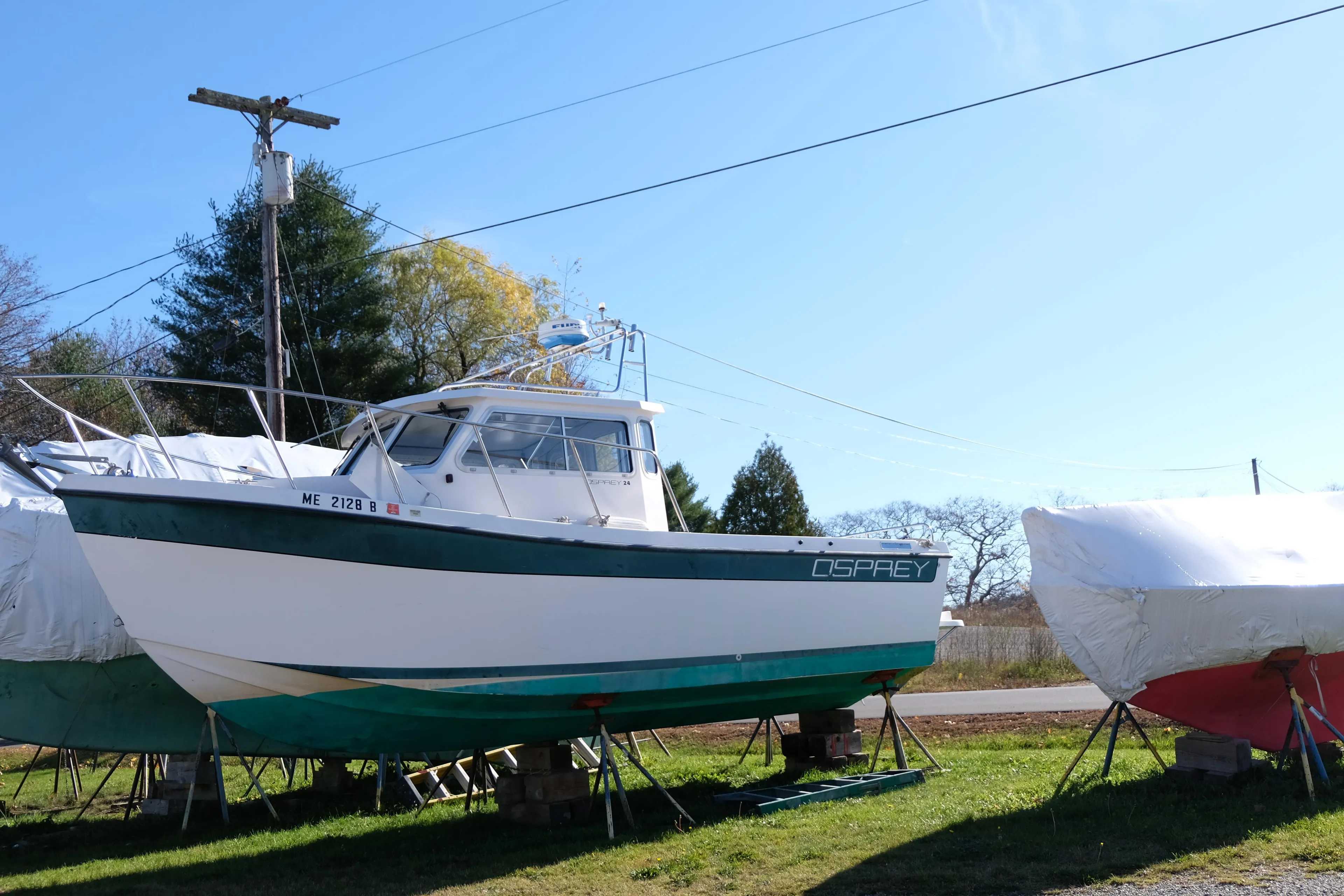 1999 Osprey 24 boat on stands, surrounded by covered boats, in a sunny outdoor setting.