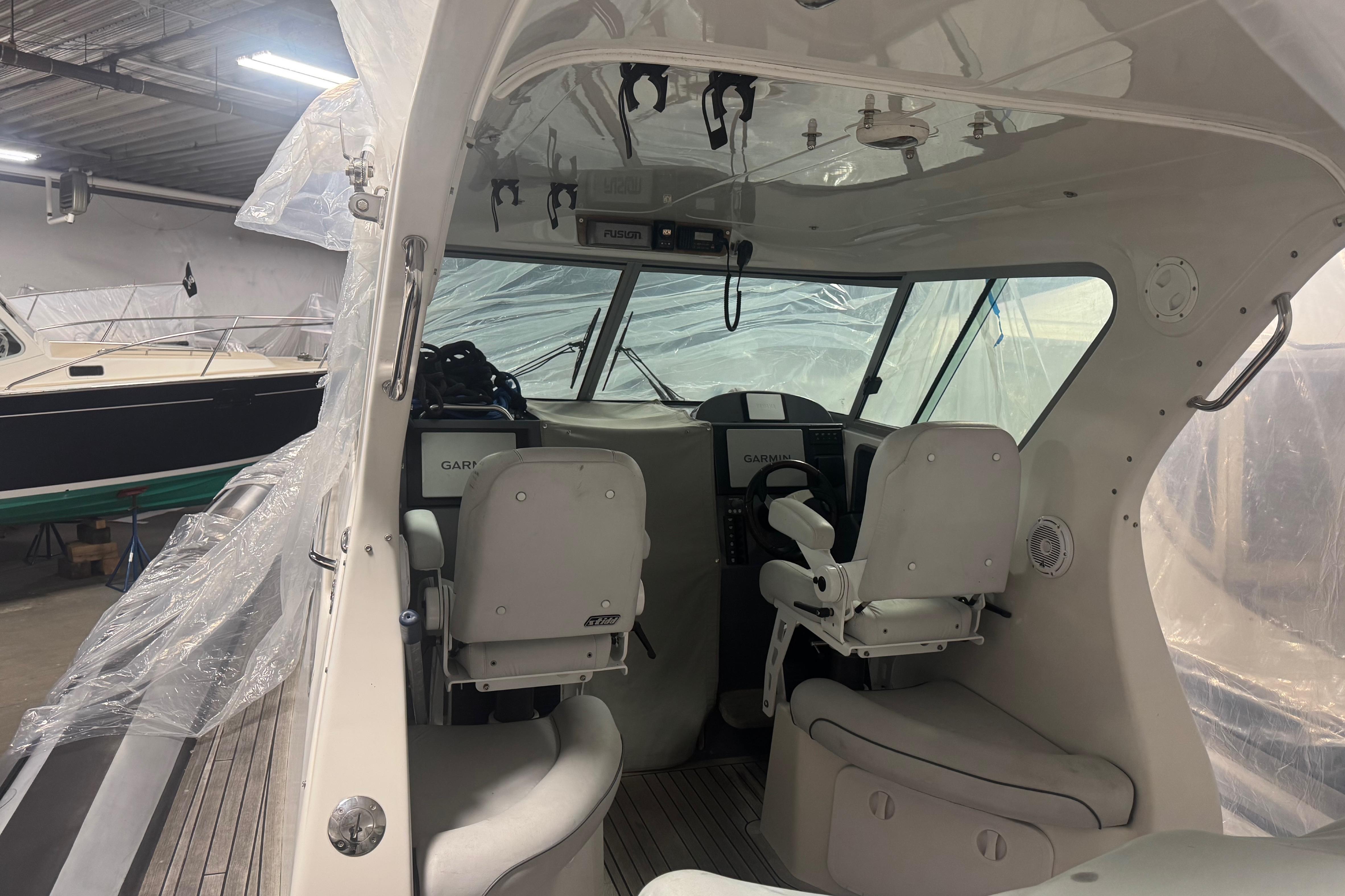 Interior of 2016 Protector Tauranga 41 boat with helm and seating in a storage facility.