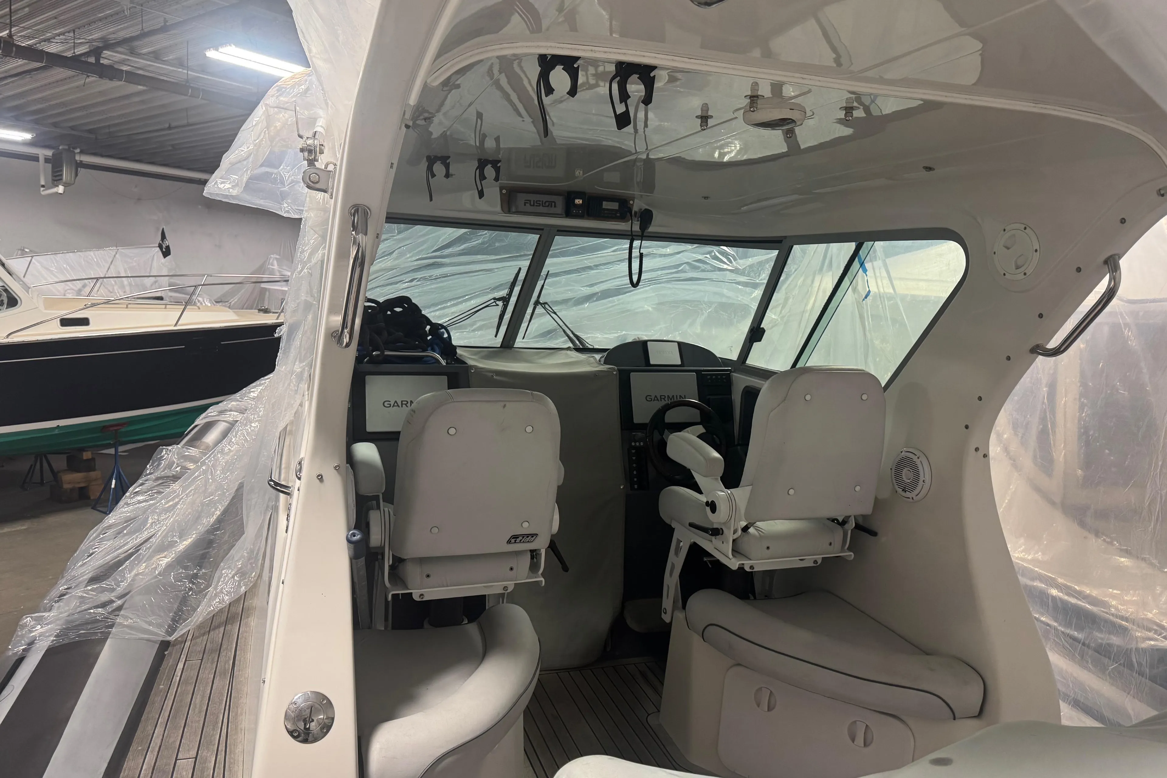 Interior of 2016 Protector Tauranga 41 boat with helm and seating in a storage facility.