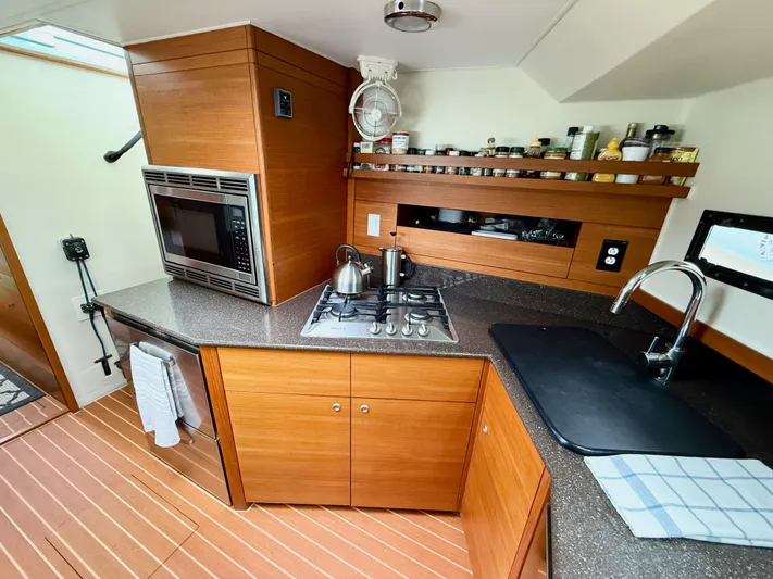 Starship Yacht Photos Pics Modern kitchen in a 2017 Gunboat 55 yacht with wood cabinetry and stainless steel appliances.