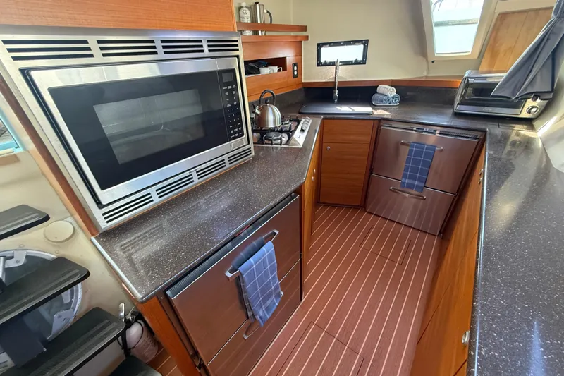Starship Yacht Photos Pics Modern kitchen in 2017 Gunboat 55 yacht with microwave, stove, and wooden cabinetry.