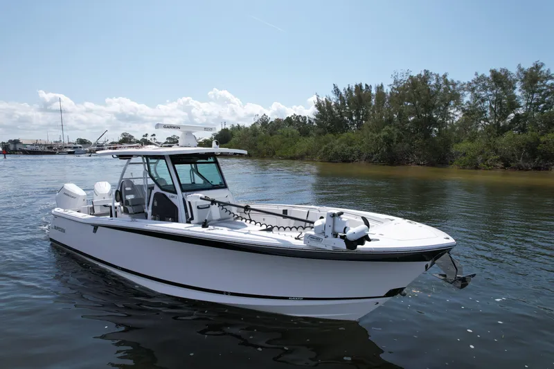  Yacht Photos Pics 2024 Blackfin 332 CC boat on calm water, surrounded by trees and clear sky.