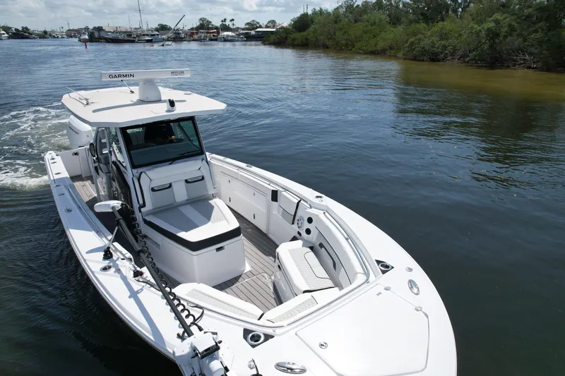  Yacht Photos Pics 2024 Blackfin 332 CC boat cruising on a calm river with lush greenery.