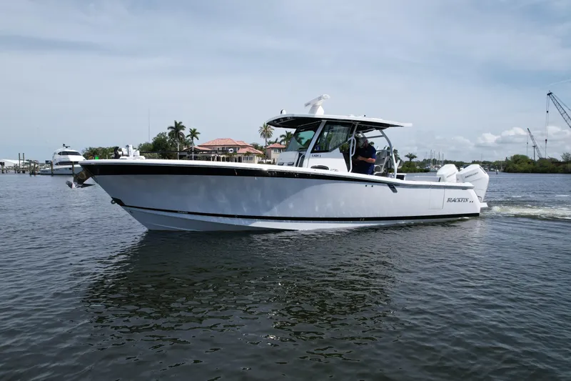  Yacht Photos Pics 2024 Blackfin 332 CC boat cruising on calm waters near a marina.