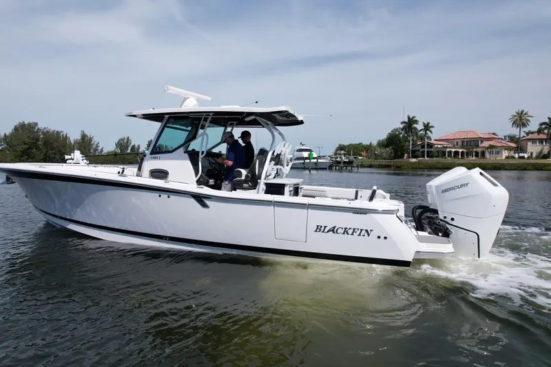  Yacht Photos Pics 2024 Blackfin 332 CC boat cruising on a calm waterway with scenic background.