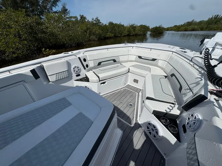 Yacht Photos Pics 2024 Blackfin 332 CC boat interior with seating and speakers, near lush greenery and water.