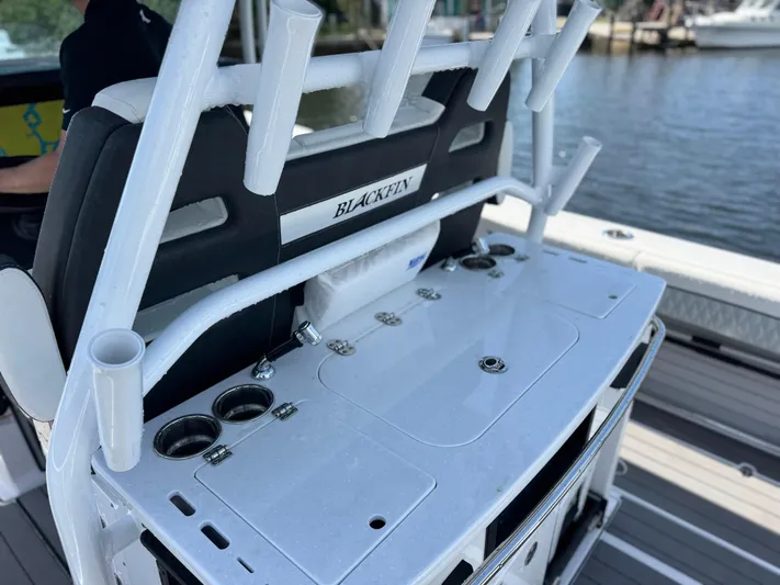  Yacht Photos Pics 2024 Blackfin 332 CC boat console with rod holders and storage, docked by the water.