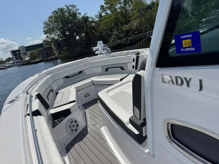  Yacht Photos Pics 2024 Blackfin 332 CC boat interior with seating, docked near lush greenery.