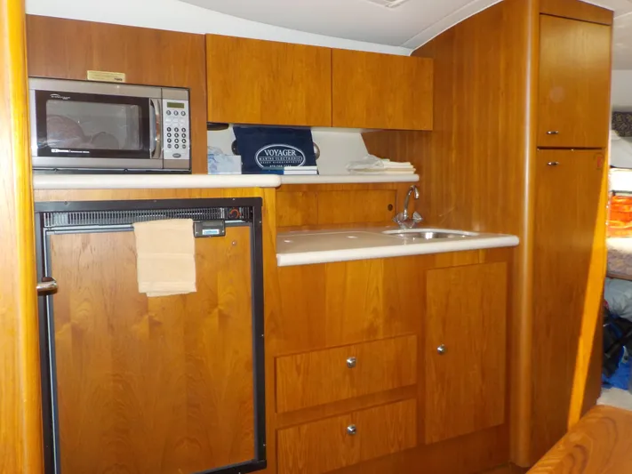 " Sea Goll " Yacht Photos Pics 2003 Tiara Yachts 3100 Open interior kitchen with microwave, sink, and wooden cabinetry.