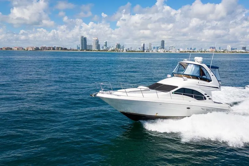 Lazy Days Yacht Photos Pics 2009 Sea Ray 44 Sedan Bridge yacht cruising near city skyline on a sunny day.