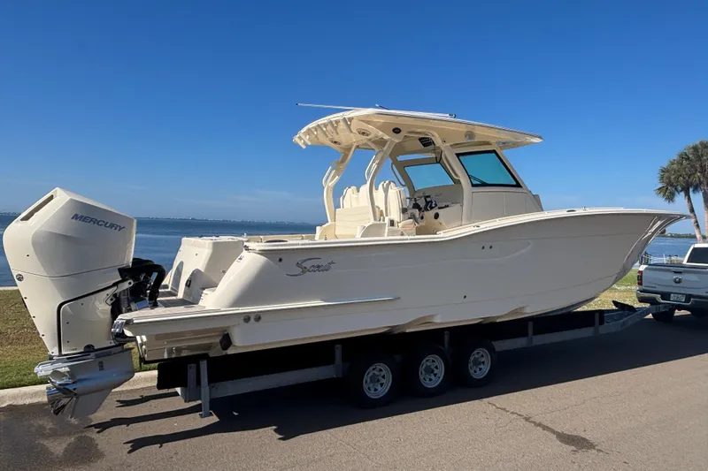  Yacht Photos Pics 2026 Scout 357 LXF boat on trailer by waterfront, featuring Mercury outboard engine.